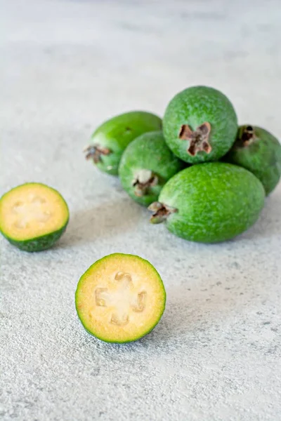 Feijoa, exotic (tropical) fruit, berry of the myrtle family, grows in the tropics and subtropics. Ripe green feijoa berries on a gray background.