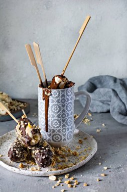 Koyu çikolata ve fındık kırıntılarıyla kaplı bir çubukta donmuş muz. Çocuklar için, doğum günü için, çikolata için hızlı ve lezzetli bir tatlı. Vejetaryen tatlı.