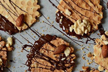 Tuzlu karamelli Hollanda gözlemeleri, tuzlu karamel ile Hollanda gözlemeleri, fındık ve gri arka planda siyah çikolata. Lezzetli çıtır tatlı. Düz yatıyordu