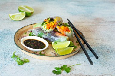 Pirinç kağıdı, çiğ sebze ve açık mavi arka planda acı soslu bitkilerden yapılmış taze Asya aperatifli börekler (Nem). Vietnam Yemekleri