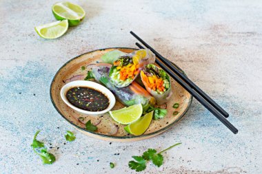 Pirinç kağıdı, çiğ sebze ve açık mavi arka planda acı soslu bitkilerden yapılmış taze Asya aperatifli börekler (Nem). Vietnam Yemekleri