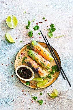 Pirinç kağıdı, çiğ sebze ve açık mavi arka planda acı soslu bitkilerden yapılmış taze Asya aperatifli börekler (Nem). Vietnam Yemekleri