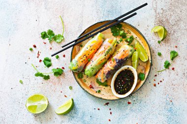 Pirinç kağıdı, çiğ sebze ve açık mavi arka planda acı soslu bitkilerden yapılmış taze Asya aperatifli börekler (Nem). Vietnam Yemekleri