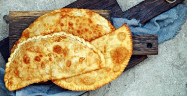 Doğu Tatar mutfağı Özbek, et, süluguni peyniri ve ahşap bir tahtanın üzerinde yeşillikler. Cheburek, etli ve soğanlı kızarmış turta. Geleneksel Türk ve Moğol yemeği, börekler börek böreği 