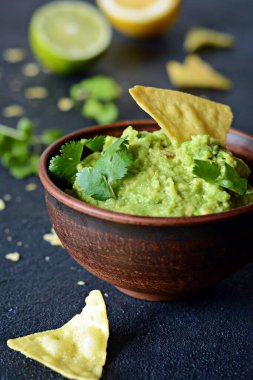 Bir kase mısır cipsli guacamole sosu ve koyu arka planda malzemeler, seçici odaklanma. Meksika ulusal yemeği.