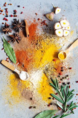 Çeşitli baharat tozları (kırmızı biber, köri, kişniş, zencefil, kurutulmuş soğan ve sarımsak, zerdeçal, tarçın, biber, anason) ve mavi bir zemin üzerinde (biberiye, defne yaprağı). Hint ve Asya mutfağı.