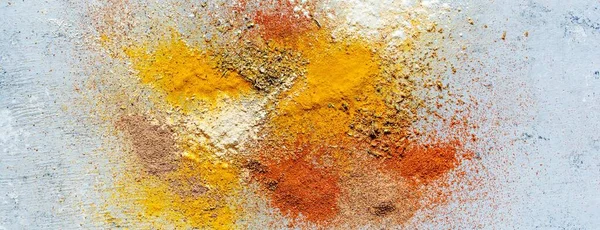 Variety of spices on a blue background. Powdered spices, dried garlic, dried onions, smoked paprika, turmeric, curry, cinnamon and coriander for cooking. Indian and Asian cuisine, Seasonings
