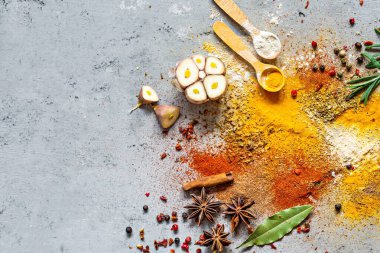 Çeşitli baharat tozları (kırmızı biber, köri, kişniş, zencefil, kurutulmuş soğan ve sarımsak, zerdeçal, tarçın, biber, anason) ve mavi bir zemin üzerinde (biberiye, defne yaprağı). Hint ve Asya mutfağı.