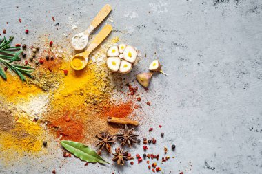 Çeşitli baharat tozları (kırmızı biber, köri, kişniş, zencefil, kurutulmuş soğan ve sarımsak, zerdeçal, tarçın, biber, anason) ve mavi bir zemin üzerinde (biberiye, defne yaprağı). Hint ve Asya mutfağı.