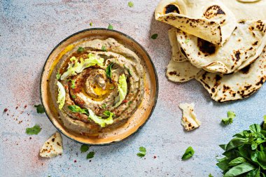 Hafif bir zemin üzerinde baharatlar, otlar, marul ve doğulu düz ekmeklerle fırında patlıcan (patlıcan püresi) içeren bir doğu yemeği..