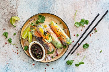 Pirinç kağıdı, çiğ sebze ve açık mavi arka planda acı soslu bitkilerden yapılmış taze Asya aperatifli börekler (Nem). Vietnam Yemekleri