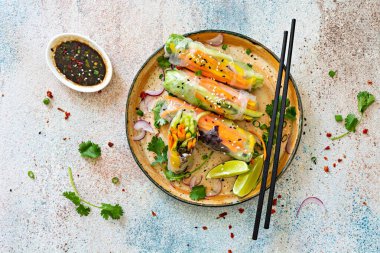 Pirinç kağıdı, çiğ sebze ve açık mavi arka planda acı soslu bitkilerden yapılmış taze Asya aperatifli börekler (Nem). Vietnam Yemekleri