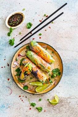 Pirinç kağıdı, çiğ sebze ve açık mavi arka planda acı soslu bitkilerden yapılmış taze Asya aperatifli börekler (Nem). Vietnam Yemekleri