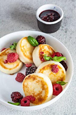 Taze süzme peynir veya taze böğürtlen ve reçelli beyaz bir tabakta ricotta krepleri (şurup, börek). Nefis sağlıklı süzme peynirli kahvaltı. Ukrayna mutfağı, Rus mutfağı tatlı yiyecekler