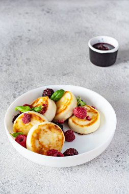 Taze süzme peynir veya taze böğürtlen ve reçelli beyaz bir tabakta ricotta krepleri (şurup, börek). Nefis sağlıklı süzme peynirli kahvaltı. Ukrayna mutfağı, Rus mutfağı tatlı yiyecekler