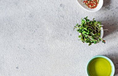 Gri arka planda zeytinyağı ve biber karışımlı bir kasede taze turp mikroçipleri. Sağlıklı yaşam tarzı konsepti, vegan yemekleri. Yeşilleniyorlar. Salata sosu..