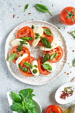 Caprese salad with juicy tomatoes, fresh mozzarella and pesto. Concept for a tasty and healthy appetizer, flat lay. Italian food, cuisine.
