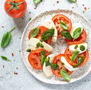 Caprese salad with juicy tomatoes, fresh mozzarella and pesto. Concept for a tasty and healthy appetizer, flat lay. Italian food, cuisine.