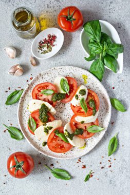 Caprese salad with juicy tomatoes, fresh mozzarella and pesto. Concept for a tasty and healthy appetizer, flat lay. Italian food, cuisine.