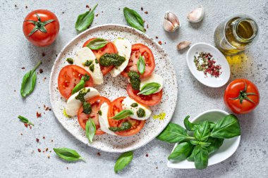 Caprese salad with juicy tomatoes, fresh mozzarella and pesto. Concept for a tasty and healthy appetizer, flat lay. Italian food, cuisine.