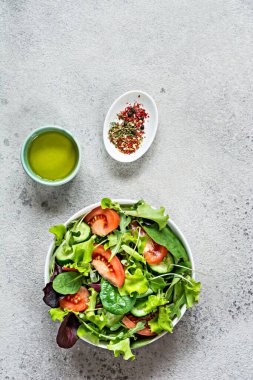 Taze sebzeli taze salata, olgun domatesler, salatalık, salatalık ve mikroyeşil gri arka planda bir kasede. Sağlıklı çiğ gıda konsepti. Metin için yer, kopyalama alanı.