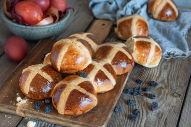 Hot cross buns with raisins, traditional English (European) pastry for Easter week on a wooden board. Delicious sweet pastries.