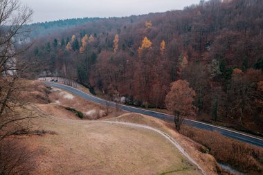 Güzel Pradnik Vadisi. Virajlı bir yol ve nehir. Krakwo-Czestochowa tepesi. Polonya. Sonbahar. Ojcow Ulusal Parkı. Suloszowa. Dönek bir yol