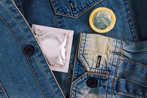 Condom in the vintage blue jeans pocket. Focus on the condom. — Stock Photo, Image