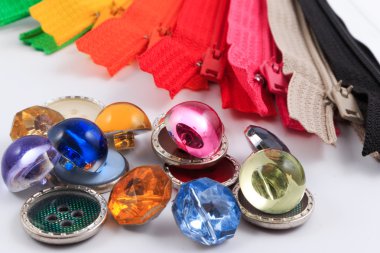 Renkli fermuarlar, kalemler ve beyaz arka plan üzerinde düğmeleri.