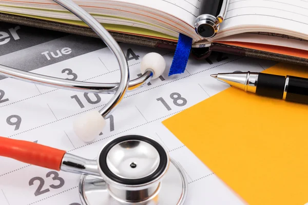 Close up of stethoscope, pen and paper note on calendar, doctor appointment. — Stock Photo, Image