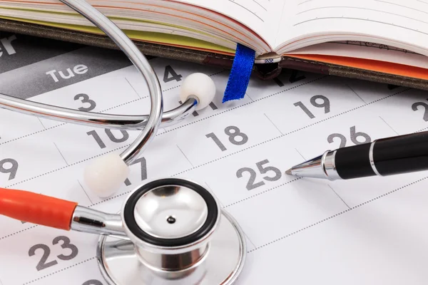 Primer plano del estetoscopio y la pluma en el calendario, cita con el médico . — Foto de Stock