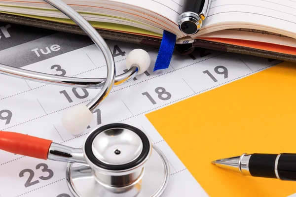 Takvimde, Doktor randevu stetoskop, kalem ve kağıt Not yakın çekim.