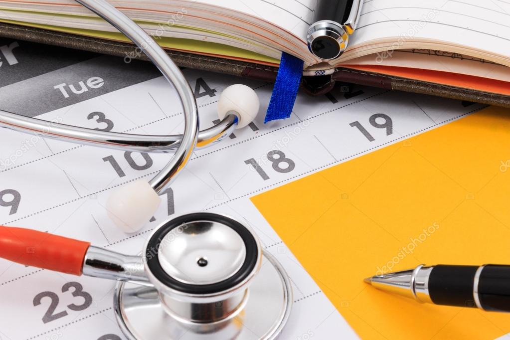 Close up of stethoscope, pen and paper note on calendar, doctor appointment.