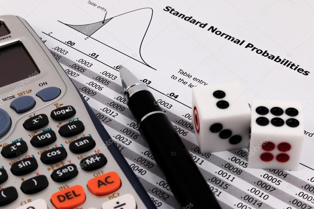 Two dice, calculator and pen on standard normal probabilities ta