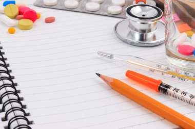 Ahşap masa üstünde boş defter ile tıbbi aksesuarları.