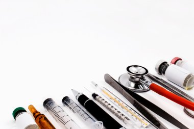 Stetoskop, şırınga, makas, pens ve ampul beyaz tıbbi çalışma yüzeyi.