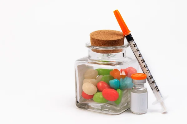 Uma seringa e um frasco de doces isolados sobre fundo branco. Proteger contra diabetes . — Fotografia de Stock