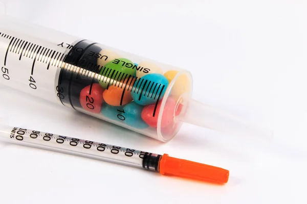 Uma seringa e um frasco de doces isolados sobre fundo branco. Proteger contra diabetes . — Fotografia de Stock