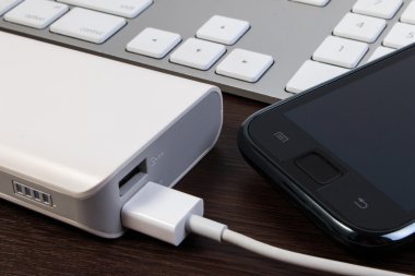 USB kablosu şarj ahşap masa üzerinde enerji banka ile.