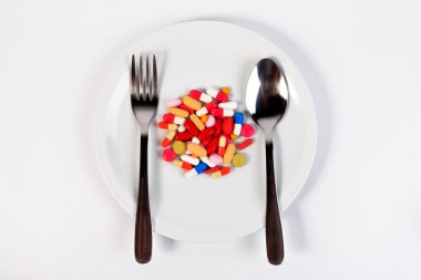 Birçok renkli hap, kapsül ve bir kaşık ile bir kase şırıngada.