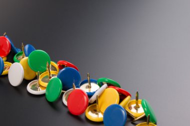 Kara tahta arka plan üzerinde renkli itme grup pimleri.