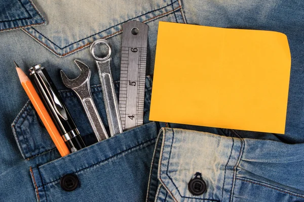 Moersleutel tools op een denim werknemers met lege Opmerking papier voor tekst. Closeup. — Stockfoto