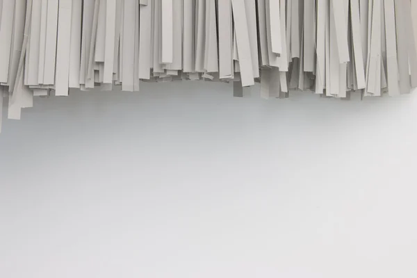 Pappers-strimlad på vit bakgrund. Paper shredder hänga på vit vägg. Strimlad dokument på vägg. — Stockfoto