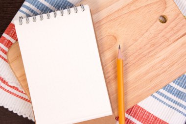 Peçete li bir kesme tahtası üzerinde mutfak tarifleri için Notebook. Ahşap arka plan üzerinde tarifi kitap açın.