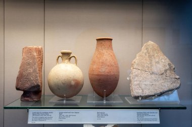 London, England - December 4, 2019: Lower part of a sandstone shabti figure of the Veceroy Setau, Cream-coated mari ware pilgrim flask from Buhen, red ware jar from Debeira and Sandstone block with sketches and hieratic inscriptions from Sesebi.