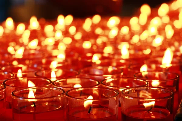 Muitas velas vermelhas queimando no interior do templo budista — Fotografia de Stock