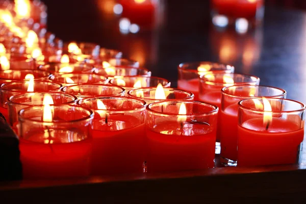 Muitas velas vermelhas queimando no interior do templo budista — Fotografia de Stock