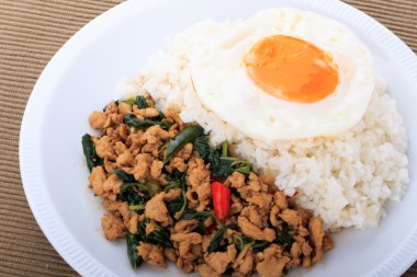 Tavada kızartılmış tavuk, fesleğen ve beyaz zemin üzerine kızarmış yumurta ile tepesinde pirinç