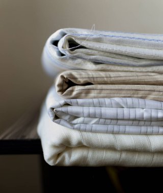 Açık renkli kumaş yığını, masanın kenarına pamuk dikme, seçici sığ odak