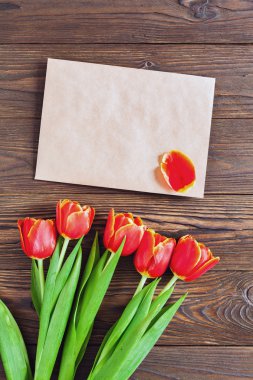 kırmızı lale ve kraft zarf ahşap arka plan üzerinde